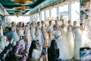 Models in white wedding dresses posing at event.